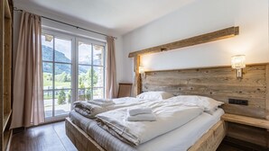Un dormitorio con cabecera de madera, un ventanal con cortinas y vistas al exterior.