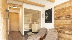 Una sala de sauna con bancos de madera y una puerta de cristal que da a un baño de vapor.