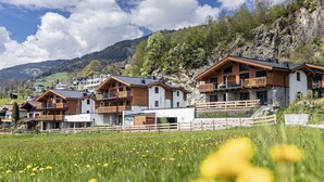 A row of wooden chalet-style buildings with balconies, set against a mountainous backdrop. - Superior Ferienhaus # 2B mit Sauna (Uttendorf)