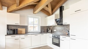 Une cuisine moderne avec des meubles blancs, un four encastré et une fenêtre qui laisse entrer la lumière naturelle.