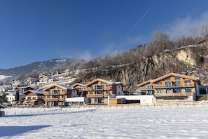 A snow-covered resort with wooden buildings, a ski slope, and a mountainous backdrop. - Superior Ferienhaus # 3B mit Sauna (Uttendorf)