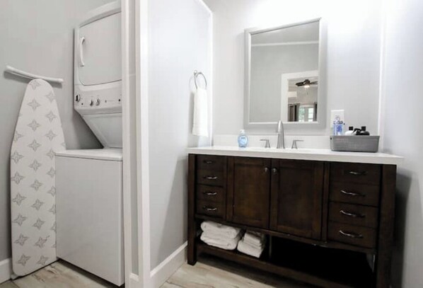 Features a spacious vanity with a large mirror, white sink, and iron.