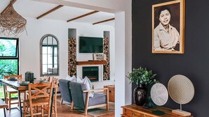 A modern living room with a fireplace, wooden furniture, and a TV mounted on the wall. - Indoni Eco Village  (Richmond)