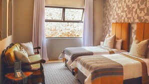 A hotel room with two beds, a sofa, a patterned rug, and a window with curtains. - Indoni Eco Village  (Richmond)