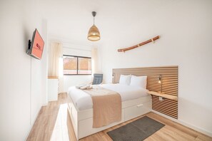 Une chambre à coucher moderne avec un lit, une table de chevet et un téléviseur fixé au mur.