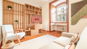 Een moderne woonkamer met een houten tv-meubel, een bureau en een gezellige zithoek.