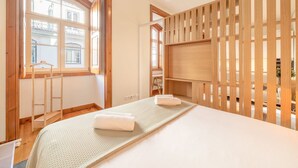 Een kamer met een bed, een houten scheiding en een raam met uitzicht op gebouwen.