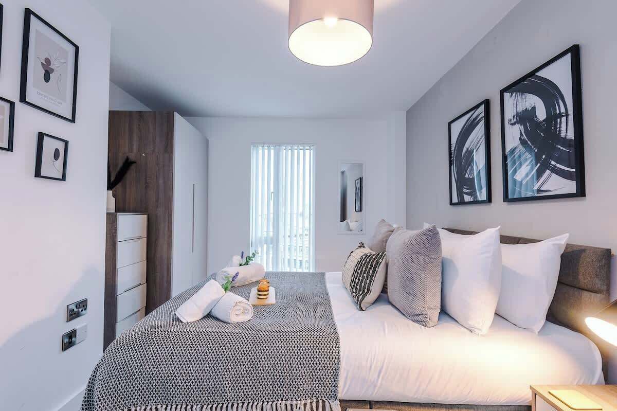 A modern bedroom with a bed, bedside table, and artwork on the walls.