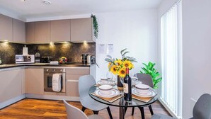 Une cuisine moderne avec un coin repas, comprenant une table en verre, des chaises et un vase rempli de fleurs.