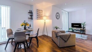Un salon moderne comprenant un coin repas, un canapé, un téléviseur et une lampe.