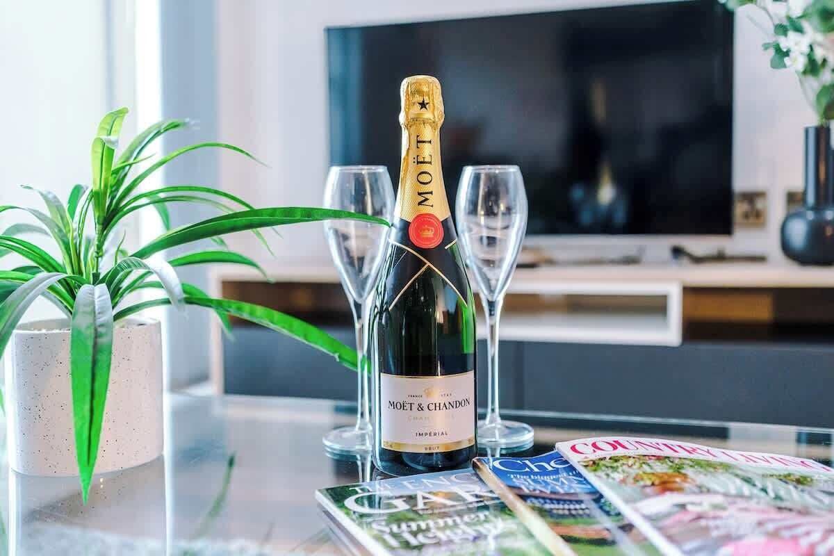 Een fles Moët & Chandon champagne op een tafel met twee glazen, een tijdschrift en een potplant.