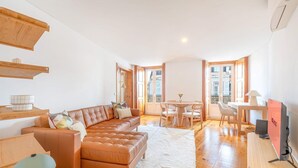 A spacious living room with a leather sofa, a dining table with chairs, and a TV on a wooden stand. - GuestReady - Night out adventure in Lisbon (Lisbon)