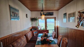A dining area with wooden paneling, a table with a floral centerpiece, and a view of the outdoors.