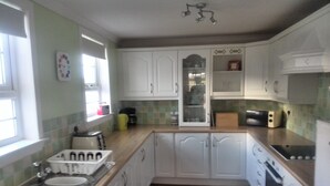 A kitchen with white cabinets, a wooden countertop, a sink, a toaster, and a microwave.