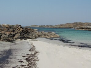 Una playa rocosa con agua turquesa cristalina y arena blanca.