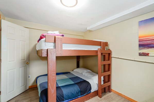 A bunk bed room with a door, a ladder, and a painting on the wall.