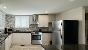 Una cocina moderna con gabinetes blancos, un refrigerador de acero inoxidable, un microondas y una estufa.