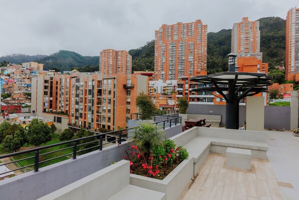 A residential area with high-rise buildings, a rooftop garden, and a modern structure with a unique design.