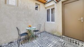 Un pequeño patio con una mesa, sillas, una puerta y baldosas con diseño.