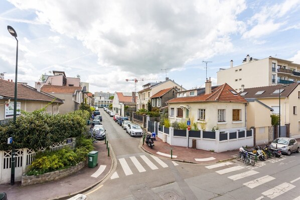 Una calle residencial con casas, automóviles estacionados y un paso de peatones.