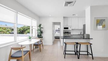 A modern kitchen with white cabinets, a black countertop, and a dining area with a round table and chairs.