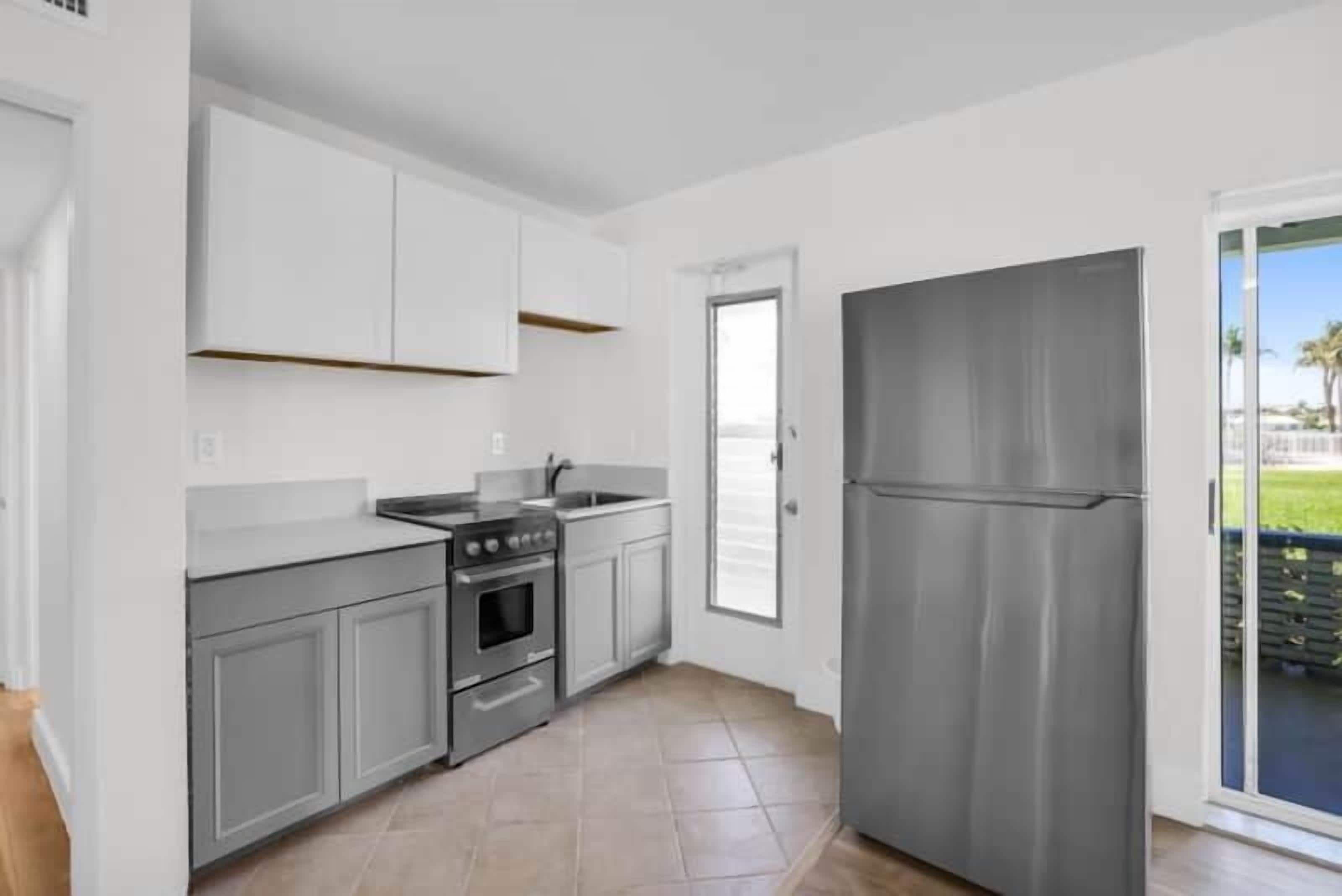 Una cucina moderna con mobili bianchi, un frigorifero in acciaio inox e un forno integrato.