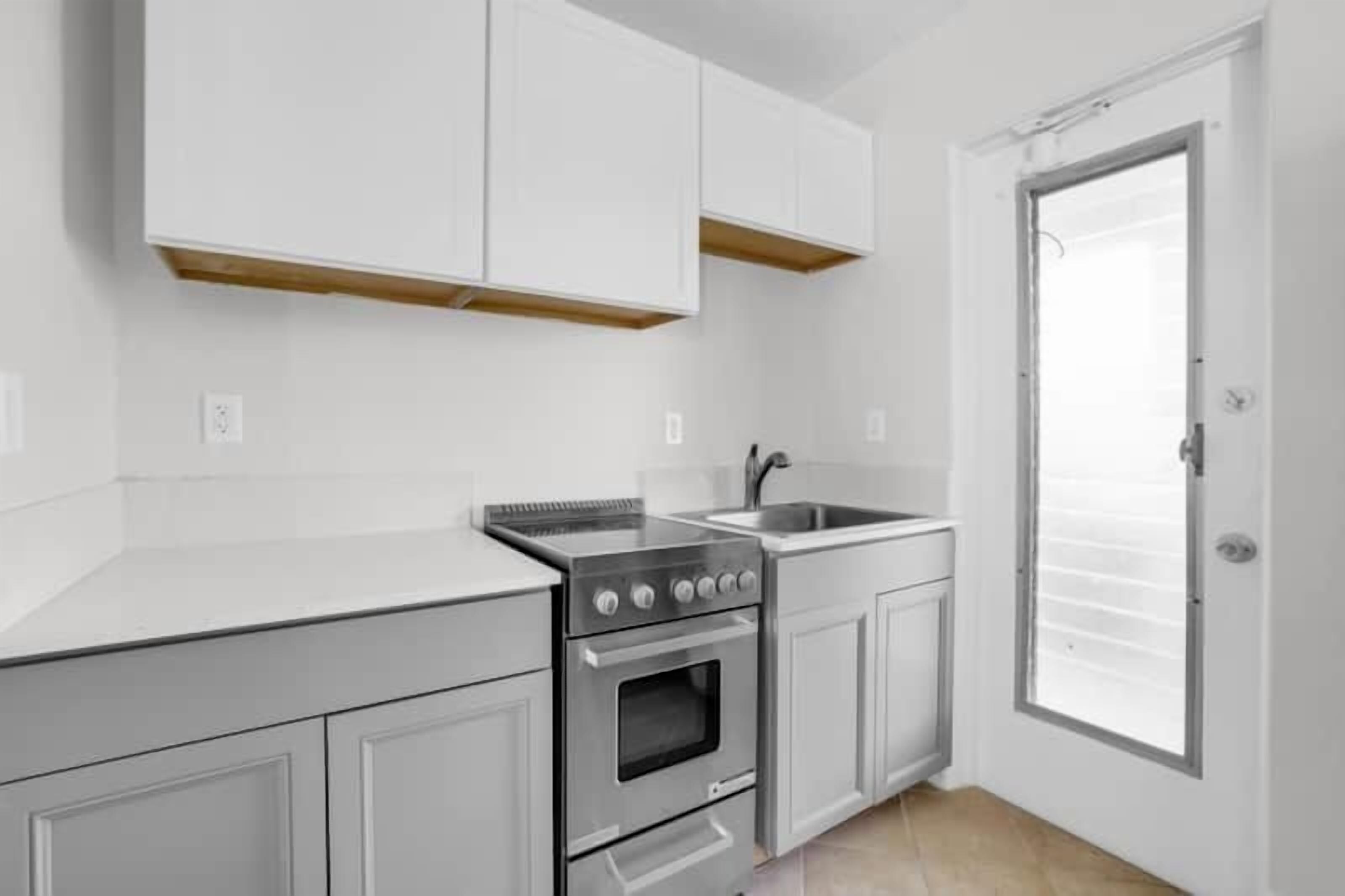A kitchen with white cabinets, a stainless steel stove, and a sink.