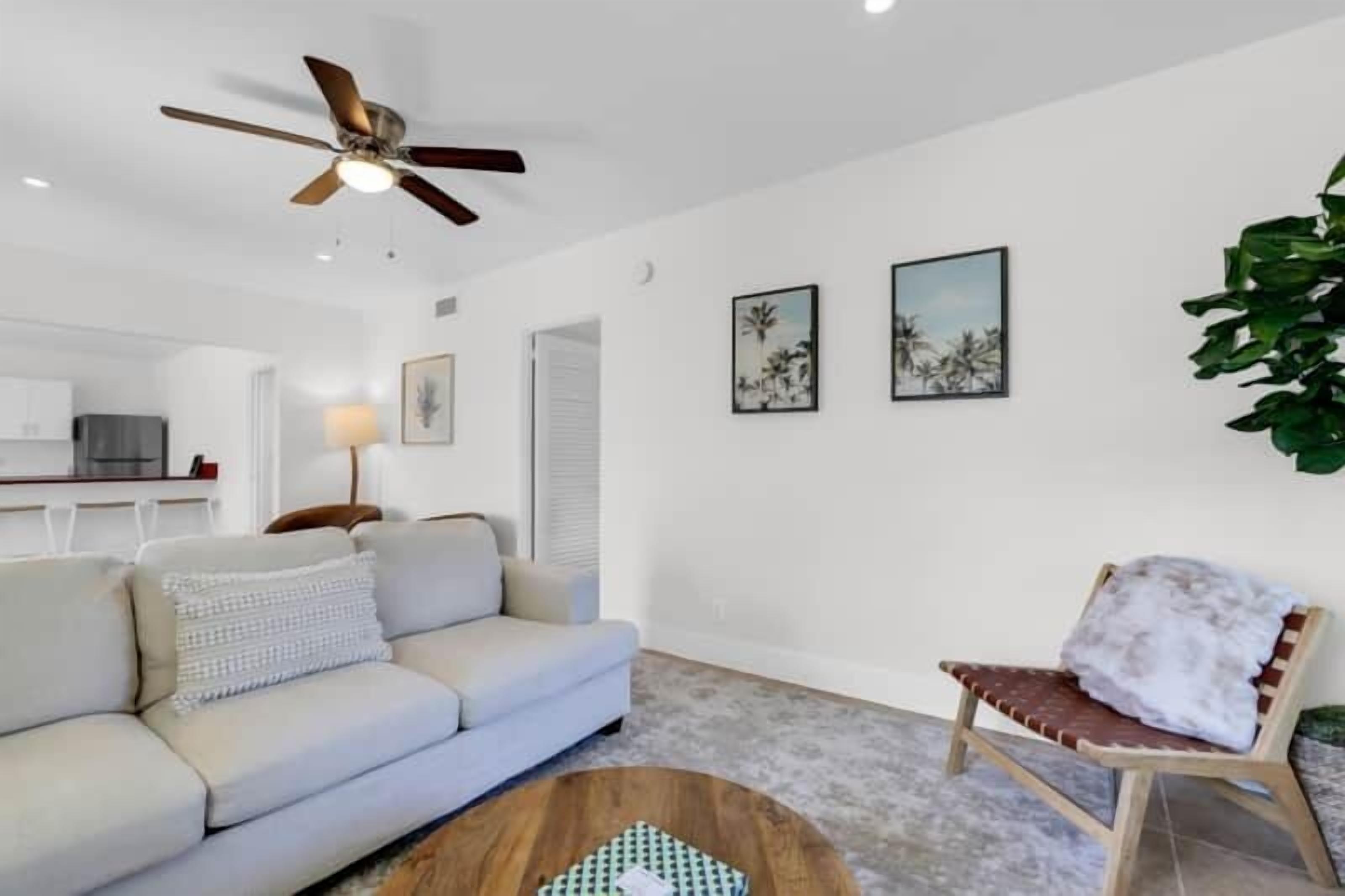 A modern living room with a ceiling fan, a sofa, a wooden coffee table, and a chair.