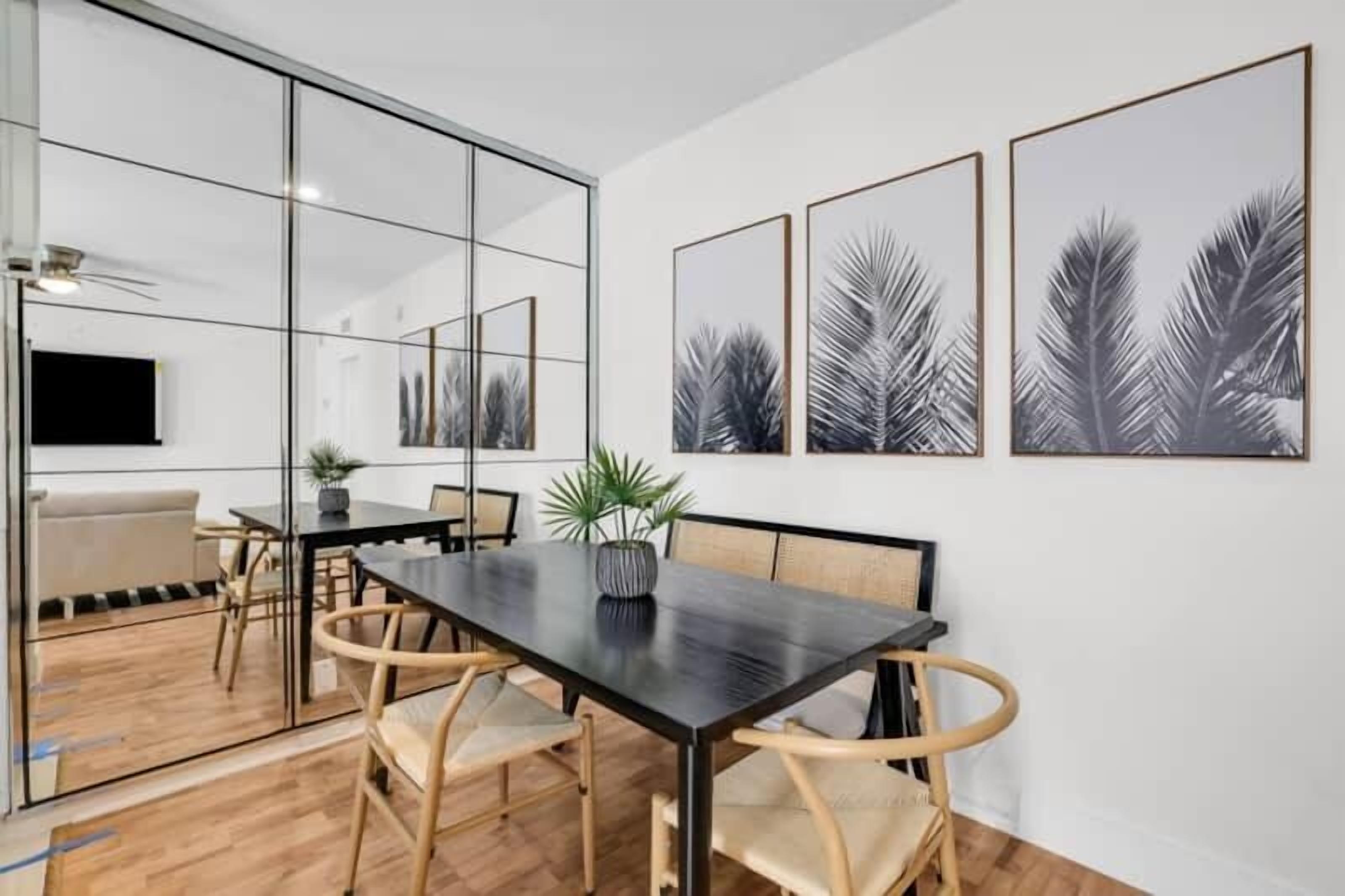 Una sala de reuniones moderna con un separador de vidrio, una mesa larga y cuatro sillas. Hay tres cuadros enmarcados en la pared.