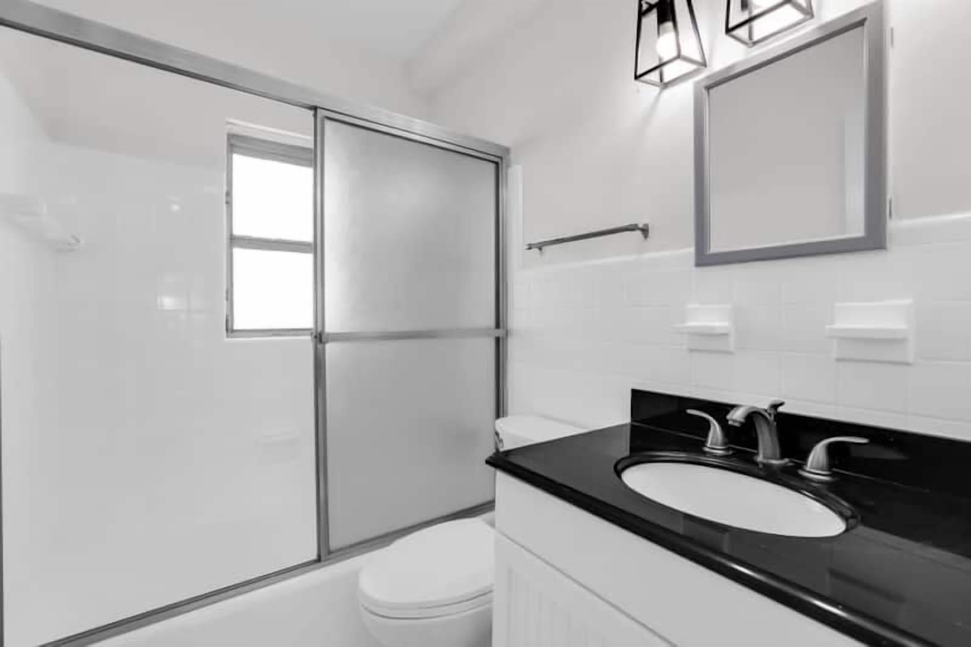 A modern bathroom with a glass shower enclosure, a black countertop sink, and a large mirror.