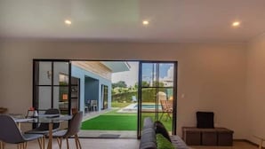 A modern living room with a glass sliding door leading to a patio. - Villa Perezosa (sloth) (La Fortuna)