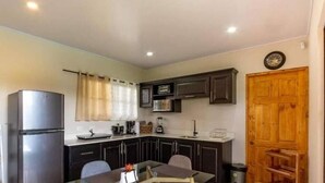 A compact kitchen with dark cabinets, a stainless steel refrigerator, a microwave, and a wooden door. - Villa Perezosa (sloth) (La Fortuna)