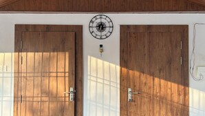 A room with wooden flooring, two large wooden doors, a white ceiling, and a hanging light fixture.