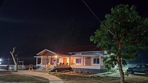 A two-story house with a porch, a small garden, and a paved driveway.