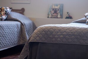 Un dormitorio con dos camas, cada una con cabecera acolchada. Hay un cuadro enmarcado en la pared.
