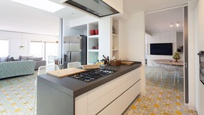 Cozinha moderna com ilha central, eletrodomésticos embutidos e área de refeições com banquetas.