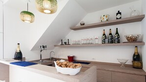 Uma cozinha moderna com ilha central, garrafas de vinho, copos e uma garrafa de champanhe.