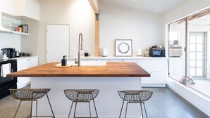 A modern kitchen with a wooden island, white cabinetry, and a large window. - Cozy 2BR Home: Hot Tub, AC, Sauna, Fire, Near Park (Joshua Tree)