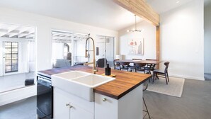 A modern kitchen with a wooden island, white cabinetry, and a large window. - Cozy 2BR Home: Hot Tub, AC, Sauna, Fire, Near Park (Joshua Tree)