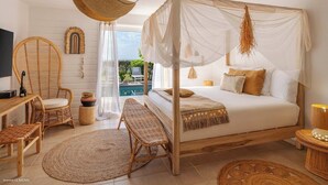 A bedroom with a four-poster bed, wicker furniture, a view of the outdoors, and a pool. - Sunset view, beach walk, heated pool (SAINT MARTIN)