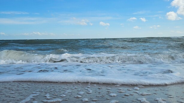 Une plage où les vagues viennent doucement lécher le rivage.