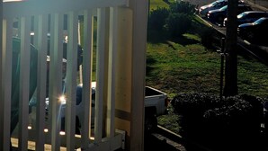Un balcon avec vue sur la mer et les voitures garées.
