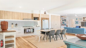 Una cocina moderna con estufa a gas, horno y refrigerador. Hay un comedor con mesa y sillas.