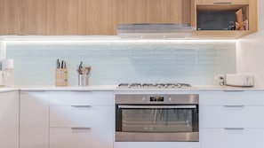 Eine moderne Küche mit Edelstahlbackofen, weißen Schränken und einer gefliesten Spritzschutzwand.