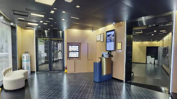 Un'accogliente area reception con scrivania, angolo salotto e ingresso con porta in vetro.