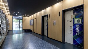 Un corridoio d'albergo con pavimento piastrellato, pareti in legno e una insegna blu e verde sulla destra.