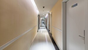 Un lungo corridoio ben illuminato con porte su entrambi i lati, che dà accesso a diverse stanze.