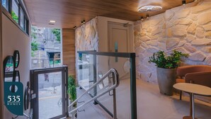 A modern interior with a stone wall, a glass door leading outside, and a seating area with a potted plant. - Stay in a Condo near Shopping da Bahia (Salvador)