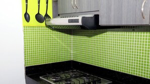 A kitchen with a gas stove, green tiled backsplash, and a yellow wall. - Vacation apartment (Cartagena de Indias)