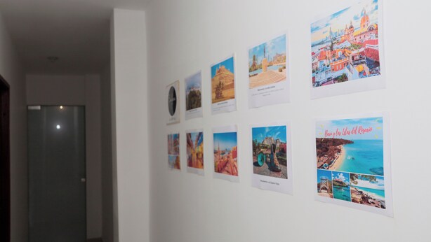 A hallway with a series of framed photographs on the wall, depicting various locations and landmarks. - Vacation apartment (Cartagena de Indias)